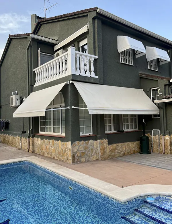 Instalación de toldos a medida de brazo articulado y capotas blancas en vivienda con piscina, fabricados por Toldos Valencia para máxima protección solar.